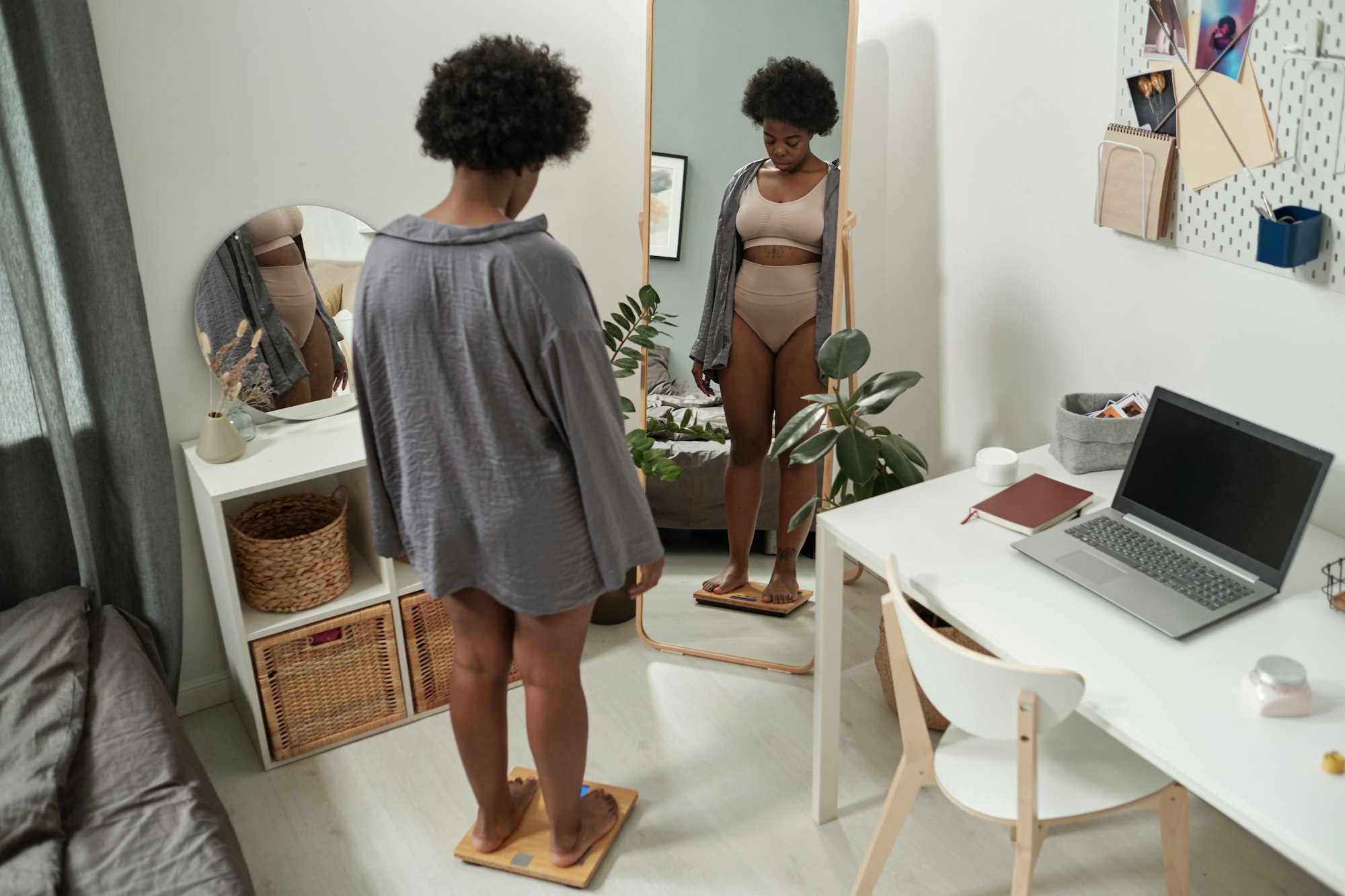 African plus size female standing on scales in bedroom