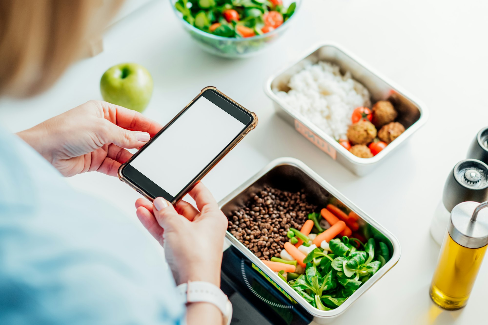 Healthy diet plan for weight loss, daily ready meal menu. Woman using phone with blank screen
